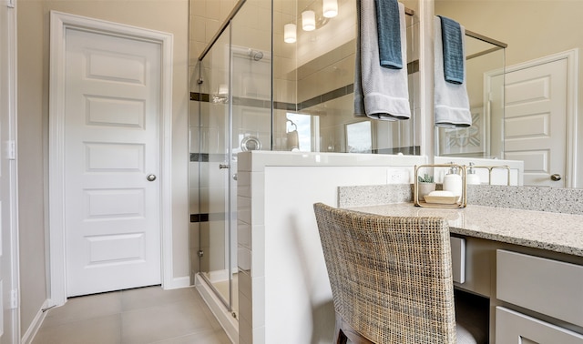 bathroom with tile patterned flooring, vanity, and walk in shower