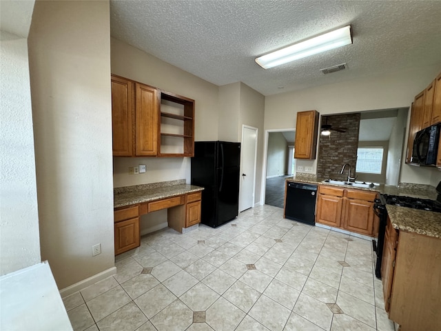 kitchen featuring built in desk, dark stone countertops, a textured ceiling, black appliances, and sink