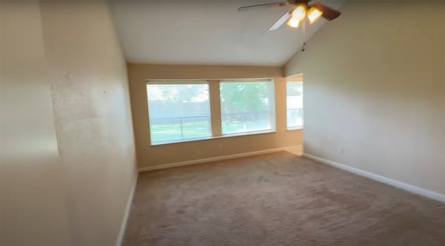 empty room featuring ceiling fan, lofted ceiling, and carpet flooring