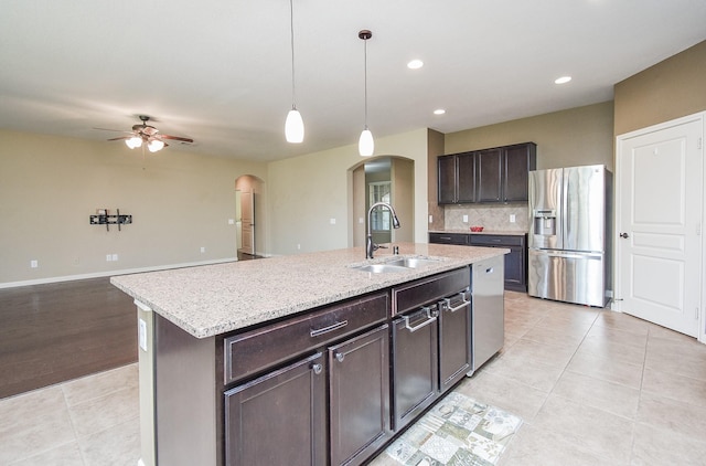 kitchen with hanging light fixtures, sink, dark brown cabinetry, stainless steel appliances, and a center island with sink