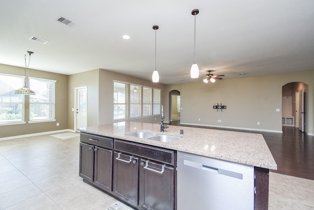 kitchen with dishwasher, sink, a kitchen island with sink, light stone counters, and dark brown cabinets