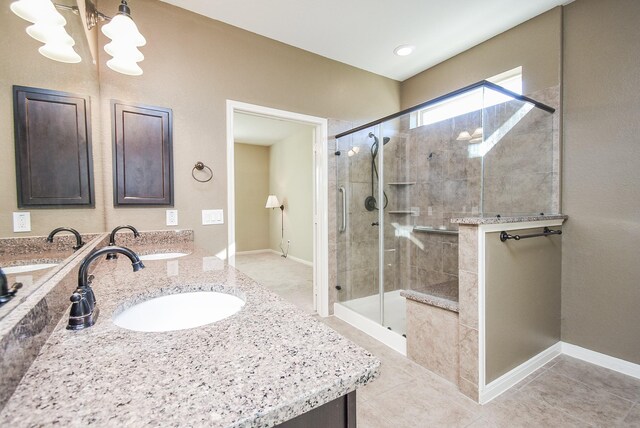 bathroom featuring an inviting chandelier, tile patterned flooring, a shower with shower door, and vanity