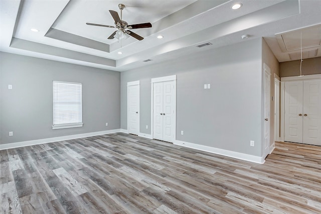 empty room featuring light hardwood / wood-style flooring, ceiling fan, and a raised ceiling