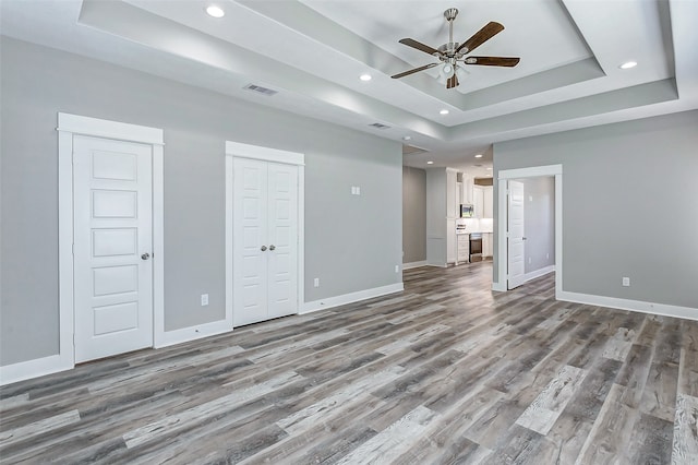 interior space featuring wood-type flooring, a tray ceiling, and ceiling fan