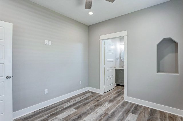 unfurnished bedroom with hardwood / wood-style floors, ensuite bath, and ceiling fan