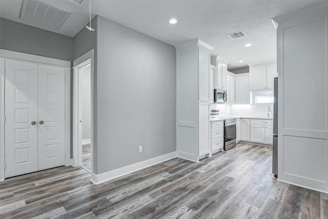 kitchen with appliances with stainless steel finishes, light hardwood / wood-style floors, and white cabinetry