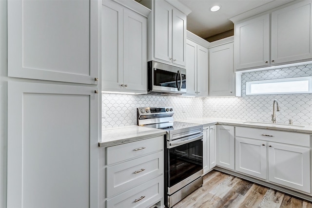 kitchen featuring light hardwood / wood-style floors, tasteful backsplash, sink, white cabinets, and stainless steel appliances