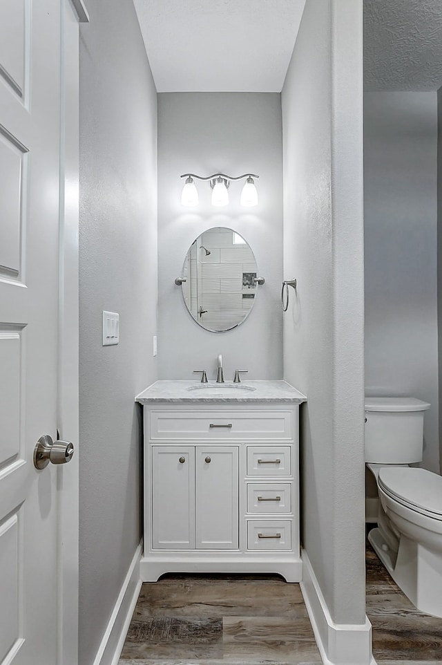 bathroom featuring wood-type flooring, vanity, and toilet