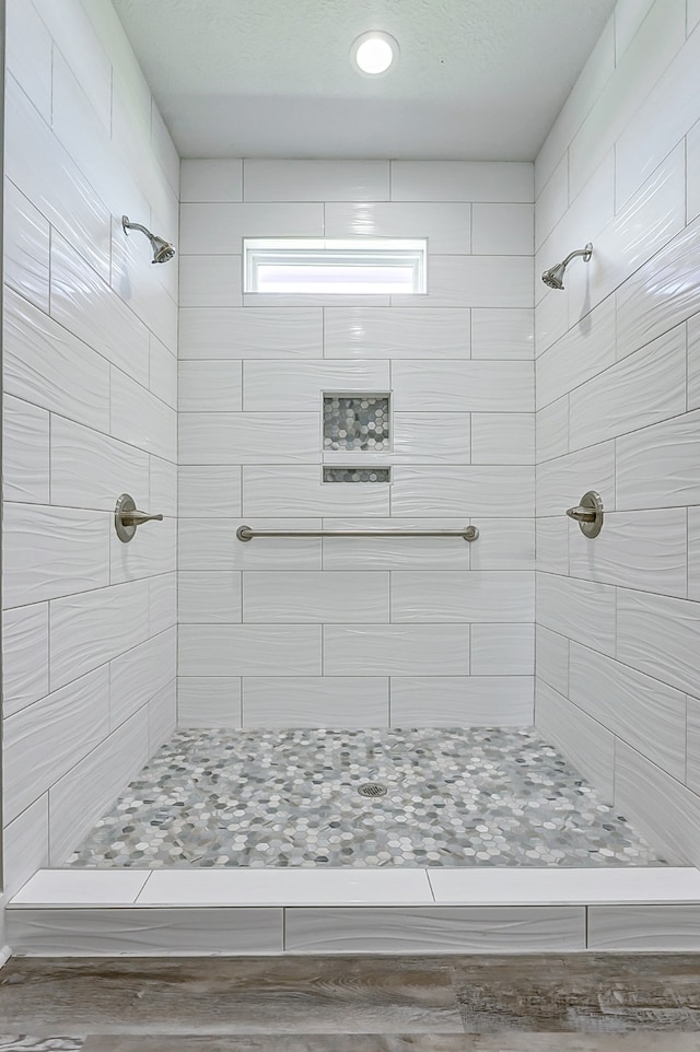 bathroom with hardwood / wood-style floors and tiled shower