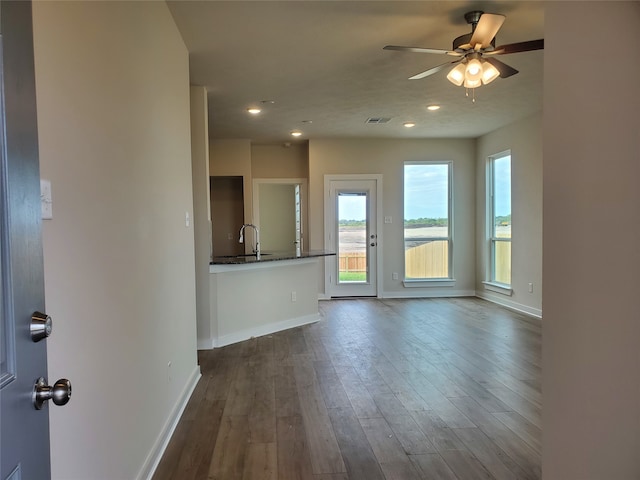 unfurnished living room featuring ceiling fan, sink, and dark hardwood / wood-style floors