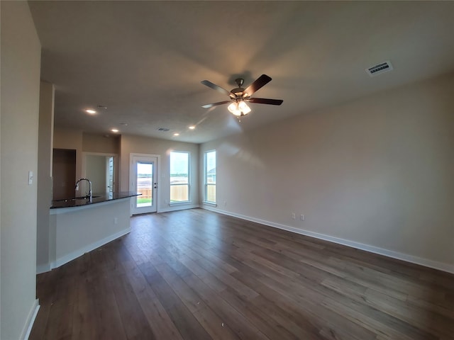 unfurnished living room with ceiling fan and dark hardwood / wood-style flooring