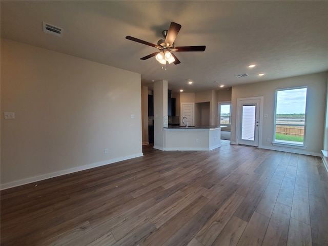 unfurnished living room featuring ceiling fan, sink, and dark wood-type flooring