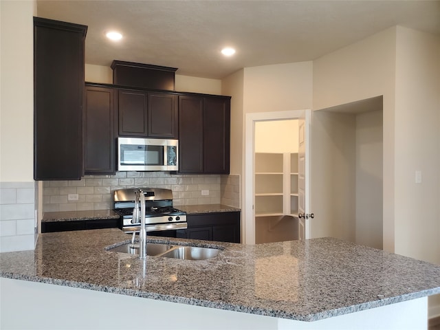 kitchen with kitchen peninsula, appliances with stainless steel finishes, backsplash, and stone countertops