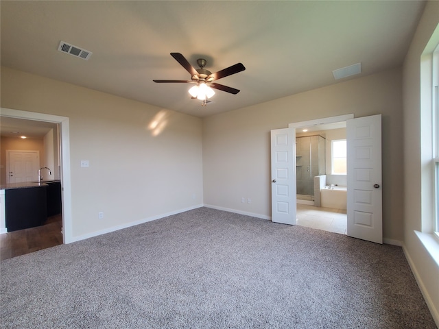 unfurnished bedroom featuring carpet flooring, ceiling fan, sink, and ensuite bath