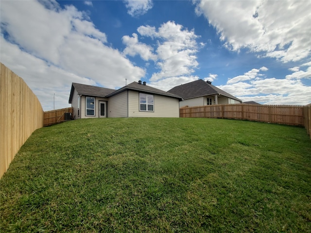 rear view of property featuring a lawn and central air condition unit