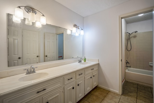 bathroom with tile patterned flooring, vanity, a textured ceiling, and tiled shower / bath