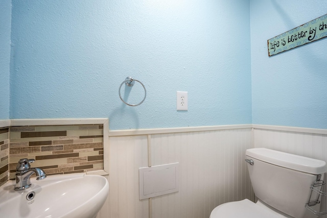 bathroom with toilet, sink, and tasteful backsplash