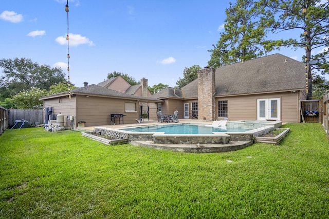 rear view of house featuring a lawn, a fenced in pool, a patio, and french doors