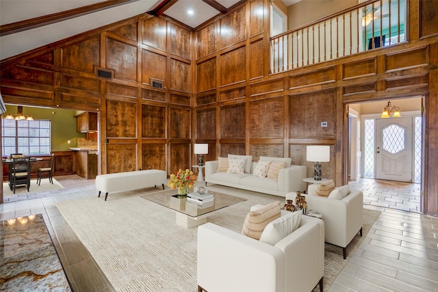 living room featuring light hardwood / wood-style flooring, high vaulted ceiling, a healthy amount of sunlight, and an inviting chandelier