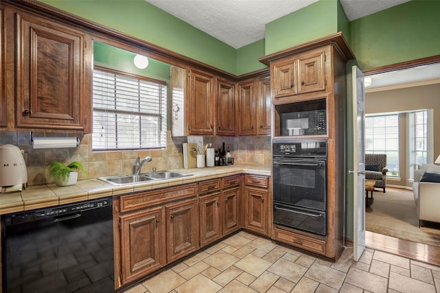 kitchen with sink, backsplash, tile counters, and black appliances