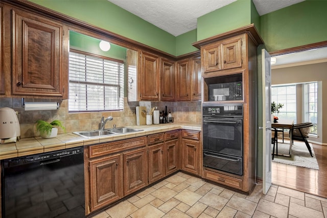 kitchen with decorative backsplash, tile counters, a healthy amount of sunlight, and black appliances