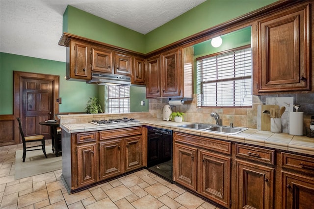 kitchen with dishwasher, sink, a healthy amount of sunlight, tile countertops, and kitchen peninsula