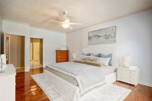 bedroom featuring hardwood / wood-style floors, a textured ceiling, ceiling fan, and ornamental molding