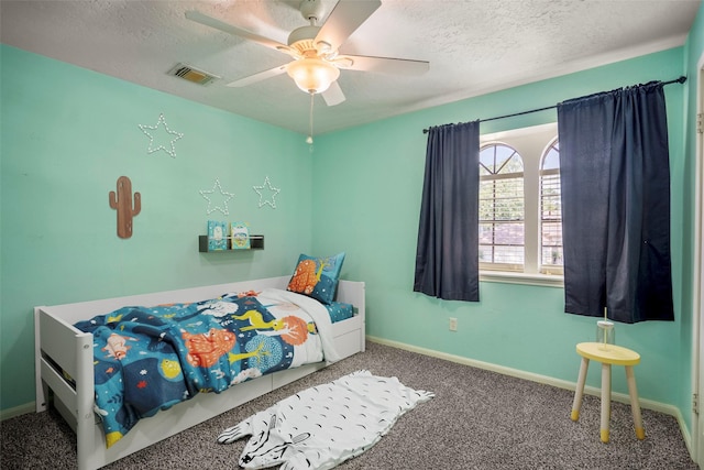 bedroom with ceiling fan, carpet floors, and a textured ceiling