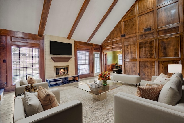 living room with beam ceiling, wood walls, a fireplace, and high vaulted ceiling