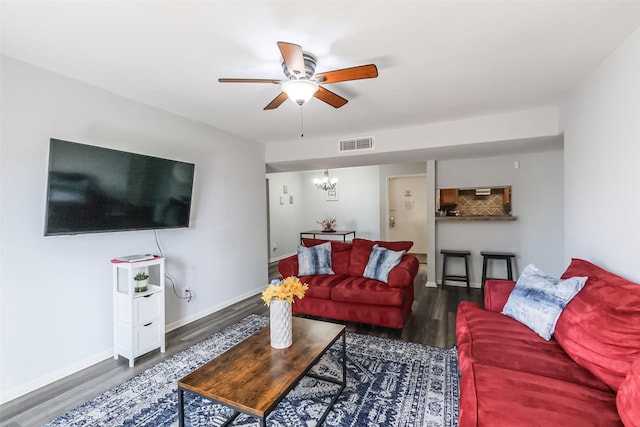 living room with ceiling fan with notable chandelier and dark wood-type flooring