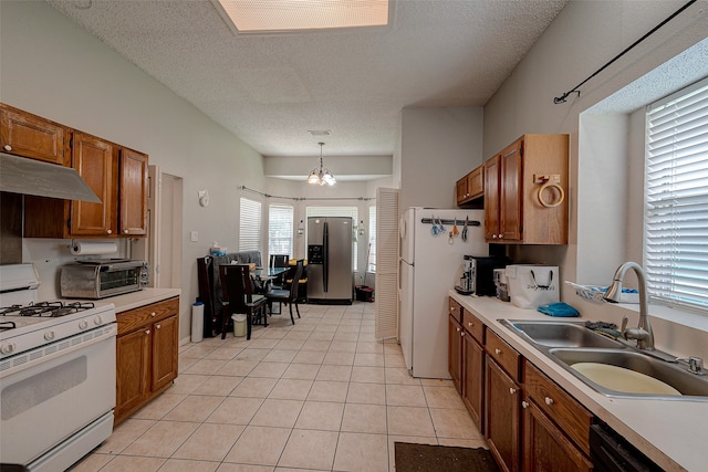 kitchen featuring decorative light fixtures, sink, white appliances, and a healthy amount of sunlight