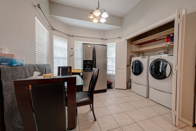 clothes washing area featuring an inviting chandelier, a wealth of natural light, light tile patterned floors, and washer and clothes dryer