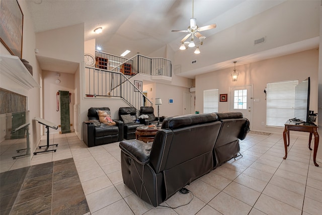 tiled living room featuring a tiled fireplace, ceiling fan, and high vaulted ceiling