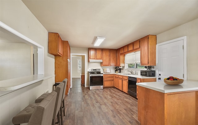 kitchen with black appliances, light hardwood / wood-style floors, and sink