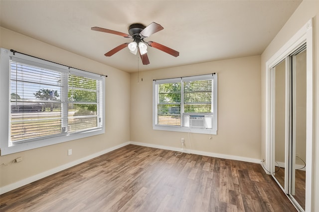 unfurnished bedroom featuring ceiling fan, cooling unit, hardwood / wood-style floors, and multiple windows