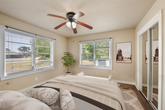 bedroom with ceiling fan, cooling unit, hardwood / wood-style floors, and multiple windows