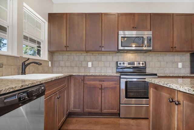 kitchen featuring light stone countertops, appliances with stainless steel finishes, dark hardwood / wood-style floors, and sink