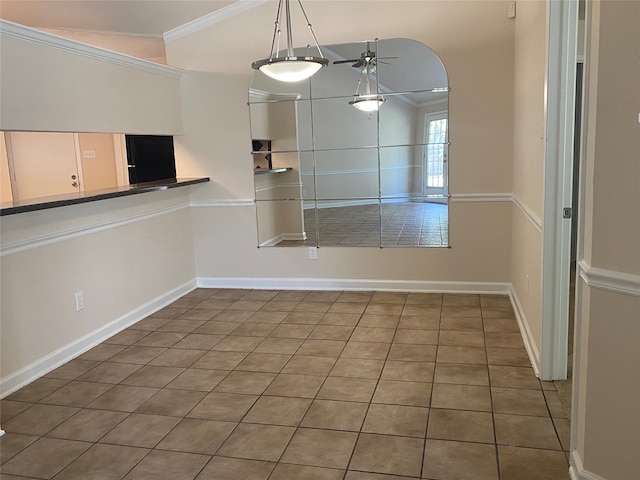 unfurnished dining area featuring ceiling fan, crown molding, and tile patterned floors