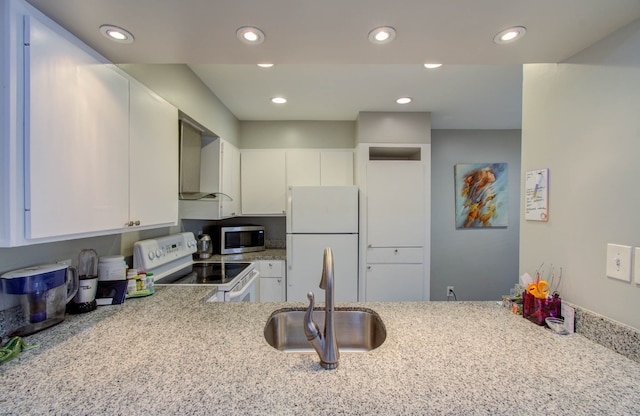 kitchen featuring wall chimney exhaust hood, sink, appliances with stainless steel finishes, and white cabinets