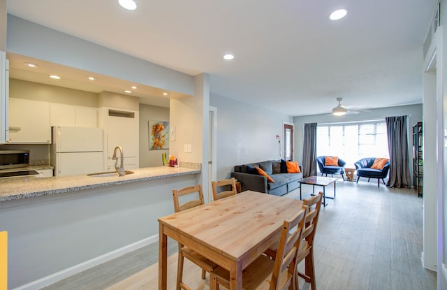 dining space featuring light hardwood / wood-style flooring, sink, and ceiling fan