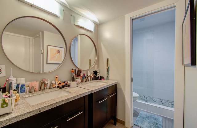 bathroom featuring vanity, toilet, a tile shower, and tile patterned flooring