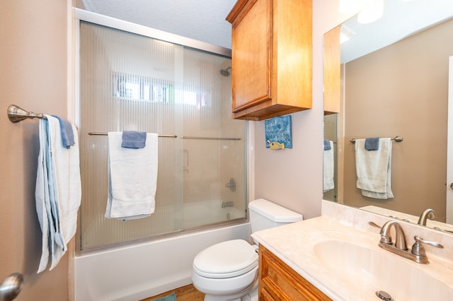 full bathroom with a textured ceiling, combined bath / shower with glass door, vanity, and toilet