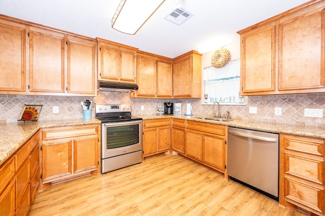 kitchen with appliances with stainless steel finishes, light hardwood / wood-style floors, backsplash, light stone countertops, and sink