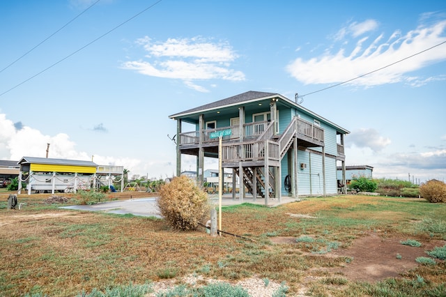 back of property with a lawn and a porch