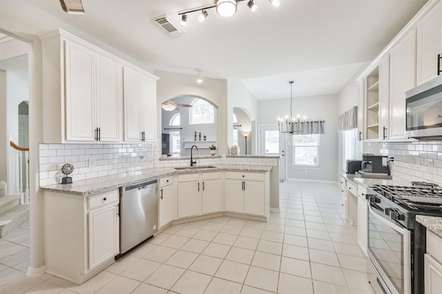 kitchen with appliances with stainless steel finishes, white cabinets, tasteful backsplash, and sink