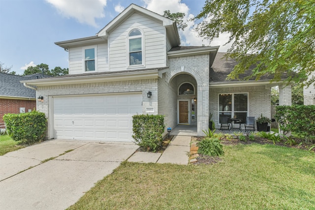 view of property featuring a front yard, covered porch, and a garage