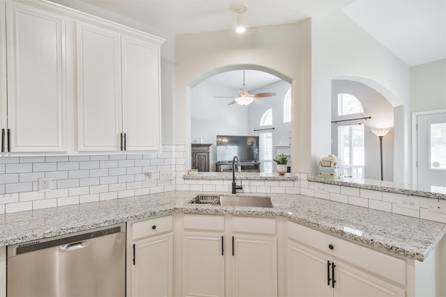 kitchen with ceiling fan, vaulted ceiling, stainless steel dishwasher, sink, and white cabinetry