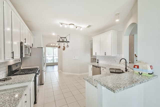 kitchen with kitchen peninsula, sink, stainless steel appliances, and white cabinetry