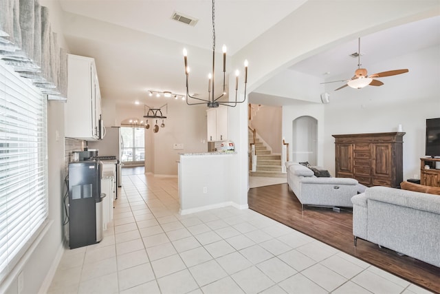 kitchen with lofted ceiling, white cabinets, ceiling fan with notable chandelier, and light tile patterned floors