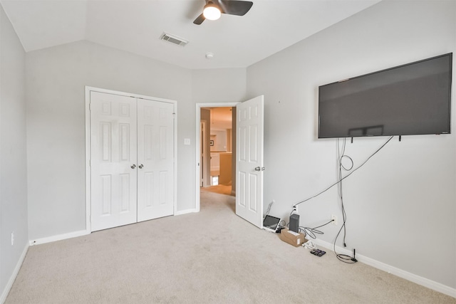 unfurnished bedroom with lofted ceiling, ceiling fan, carpet, and a closet